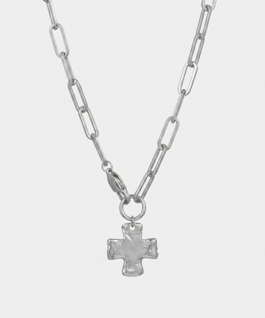 A silver paperclip chain necklace with a textured, hammered cross pendant, displayed against a light gray background.